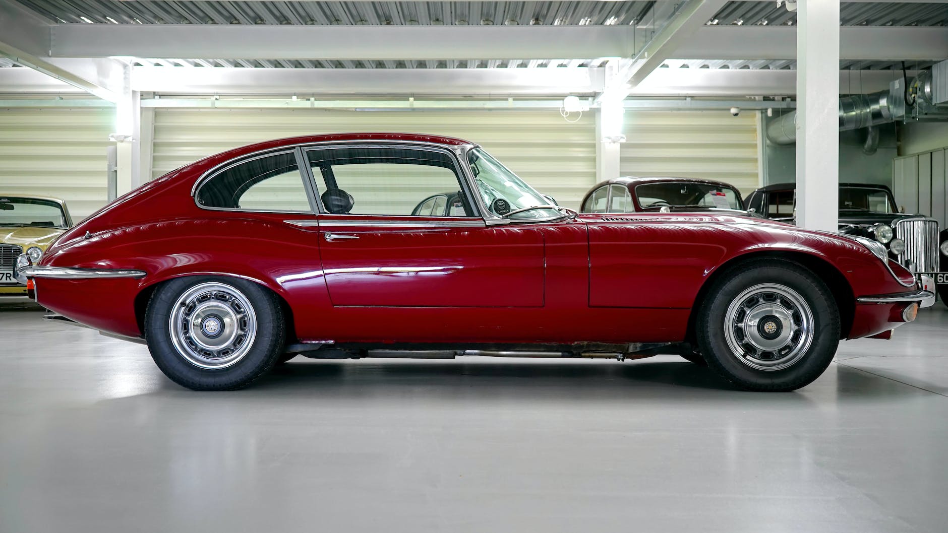 Red classic Jaguar E-Type coupe parked in a garage