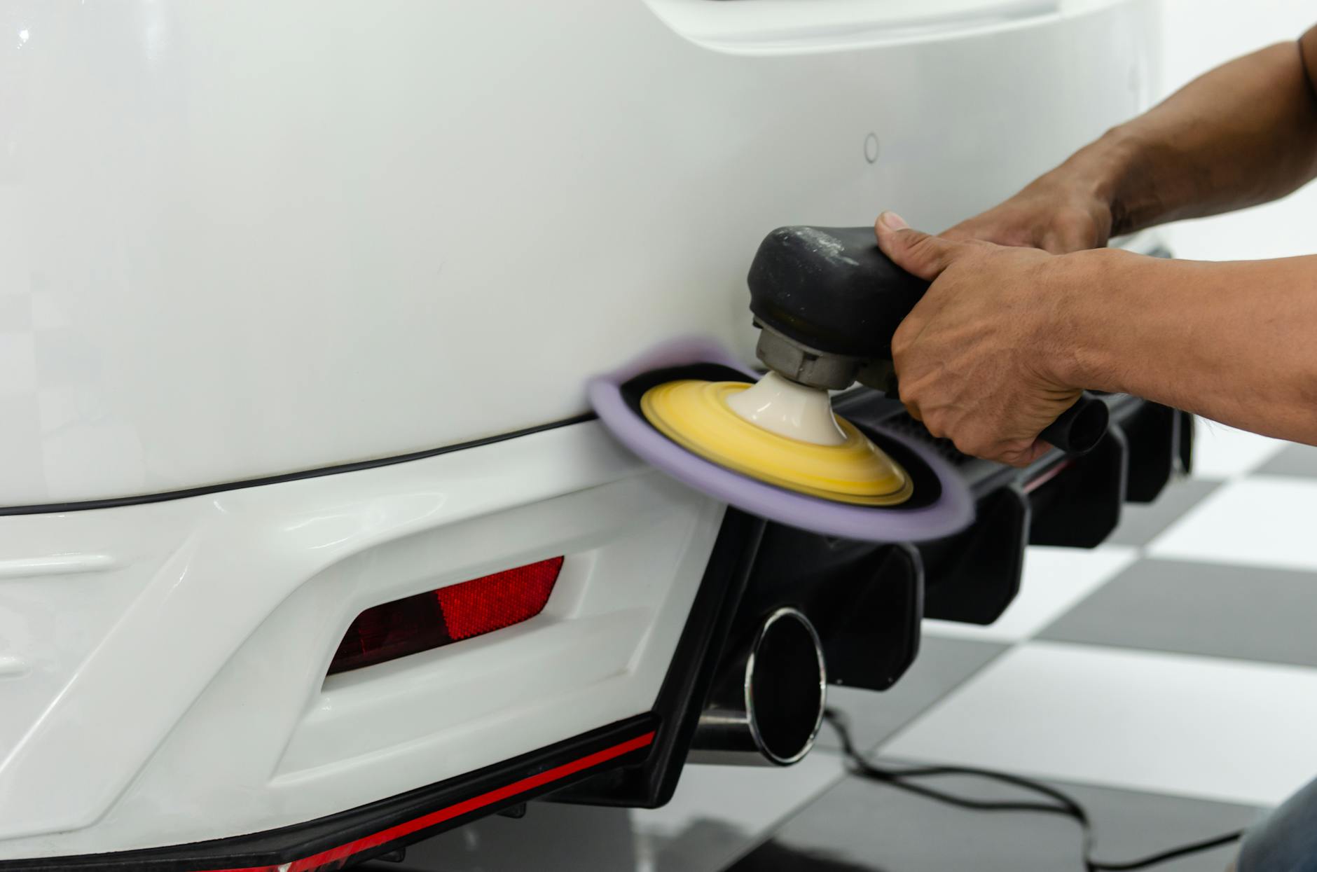 person polishing the back of the white car