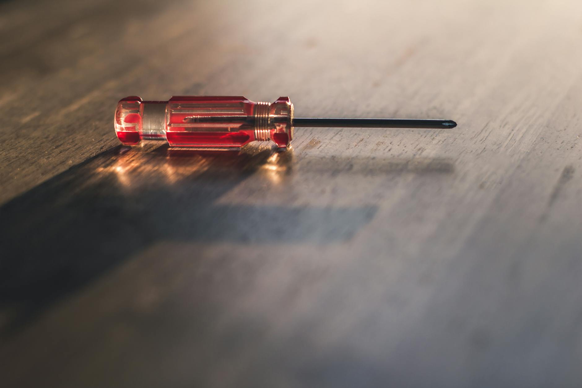 red screw driver on brown wooden surface