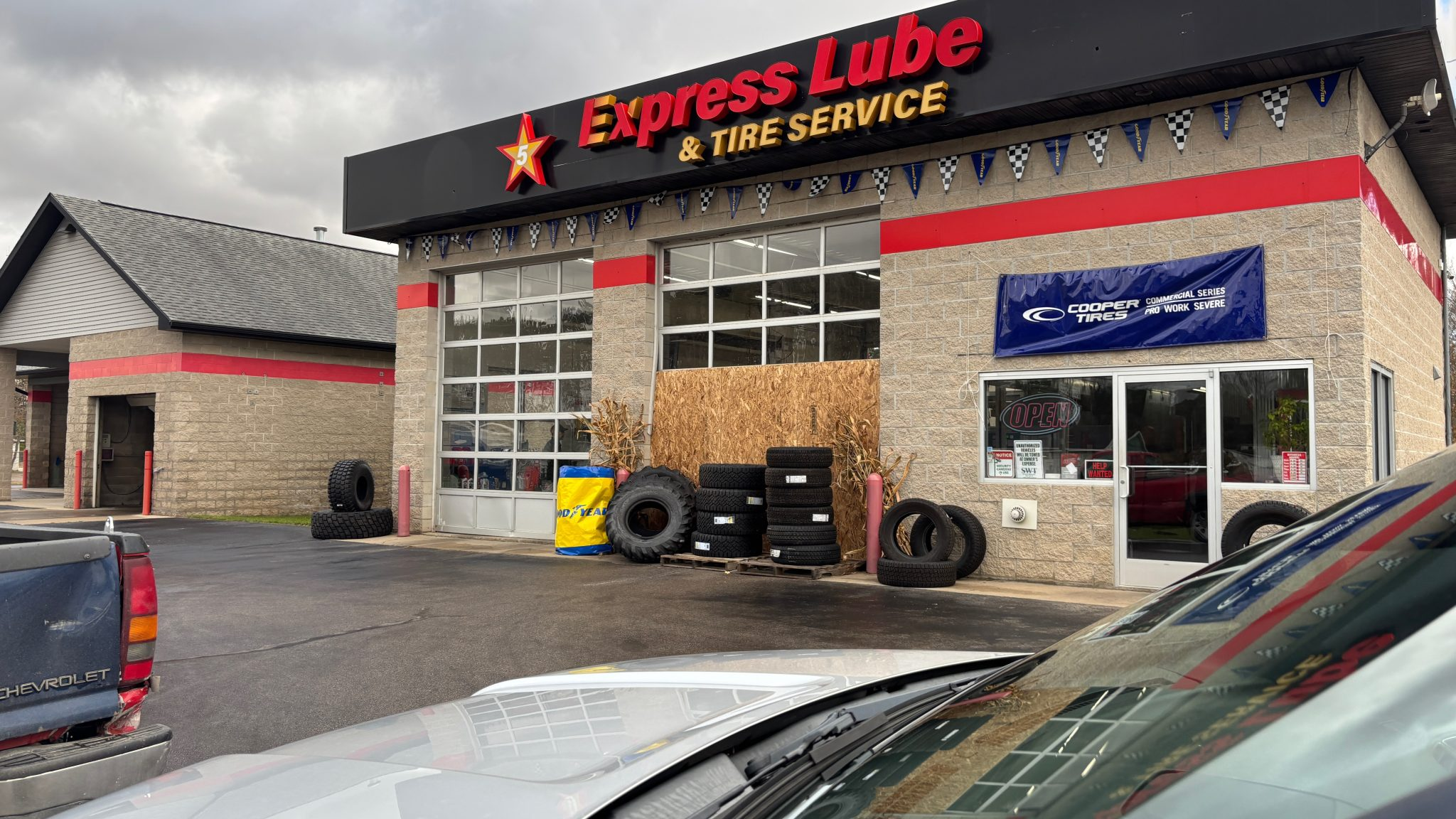 The front of an oil change store, with one garage door covered by boards and tires.