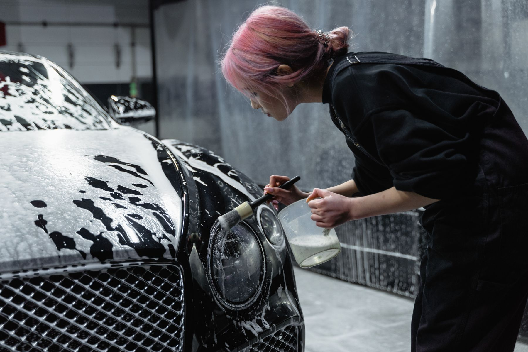 A person cleaning a car headlight lens during restoration