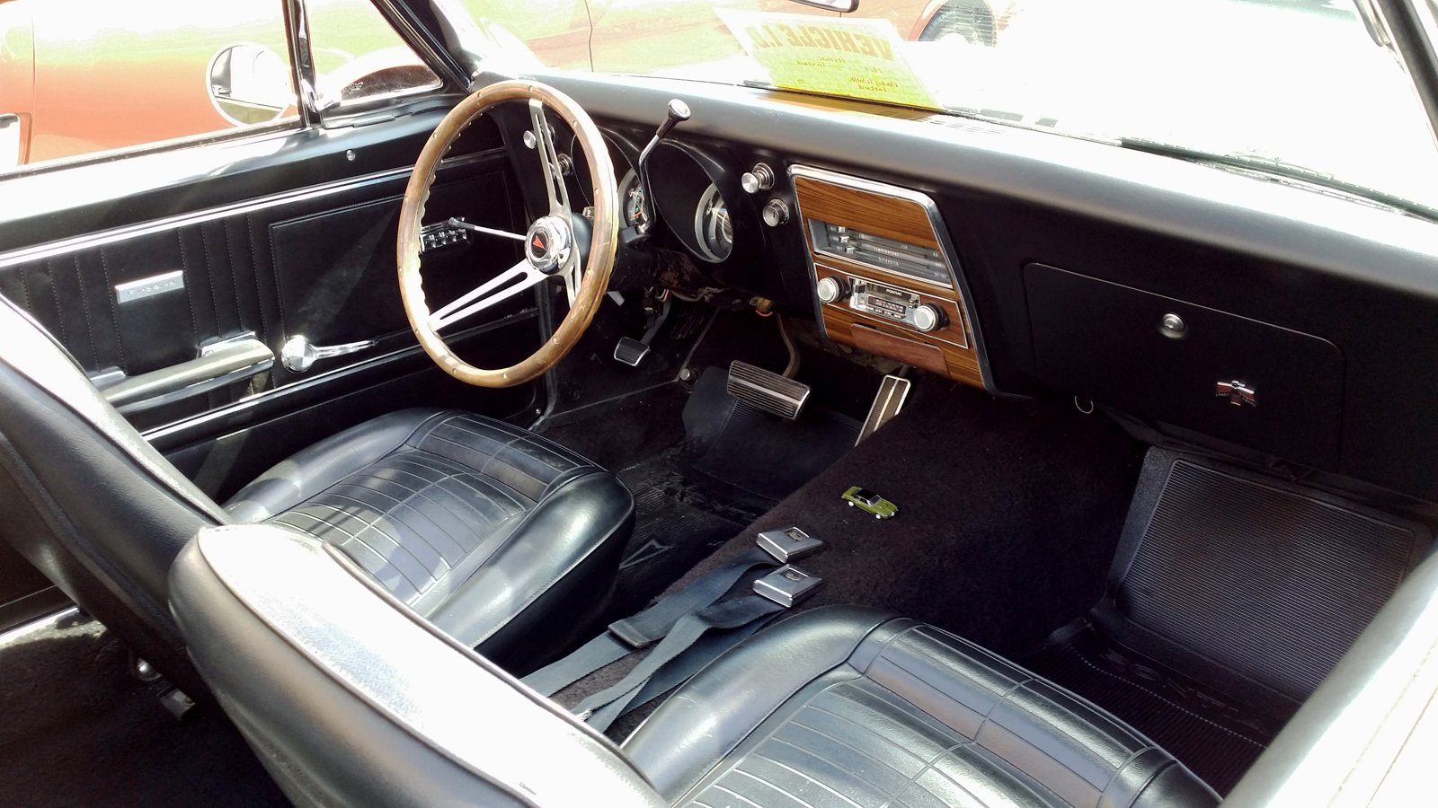 1967 Pontiac Firebird with the driver door open, showing the black bucket seats, steering wheel and dash