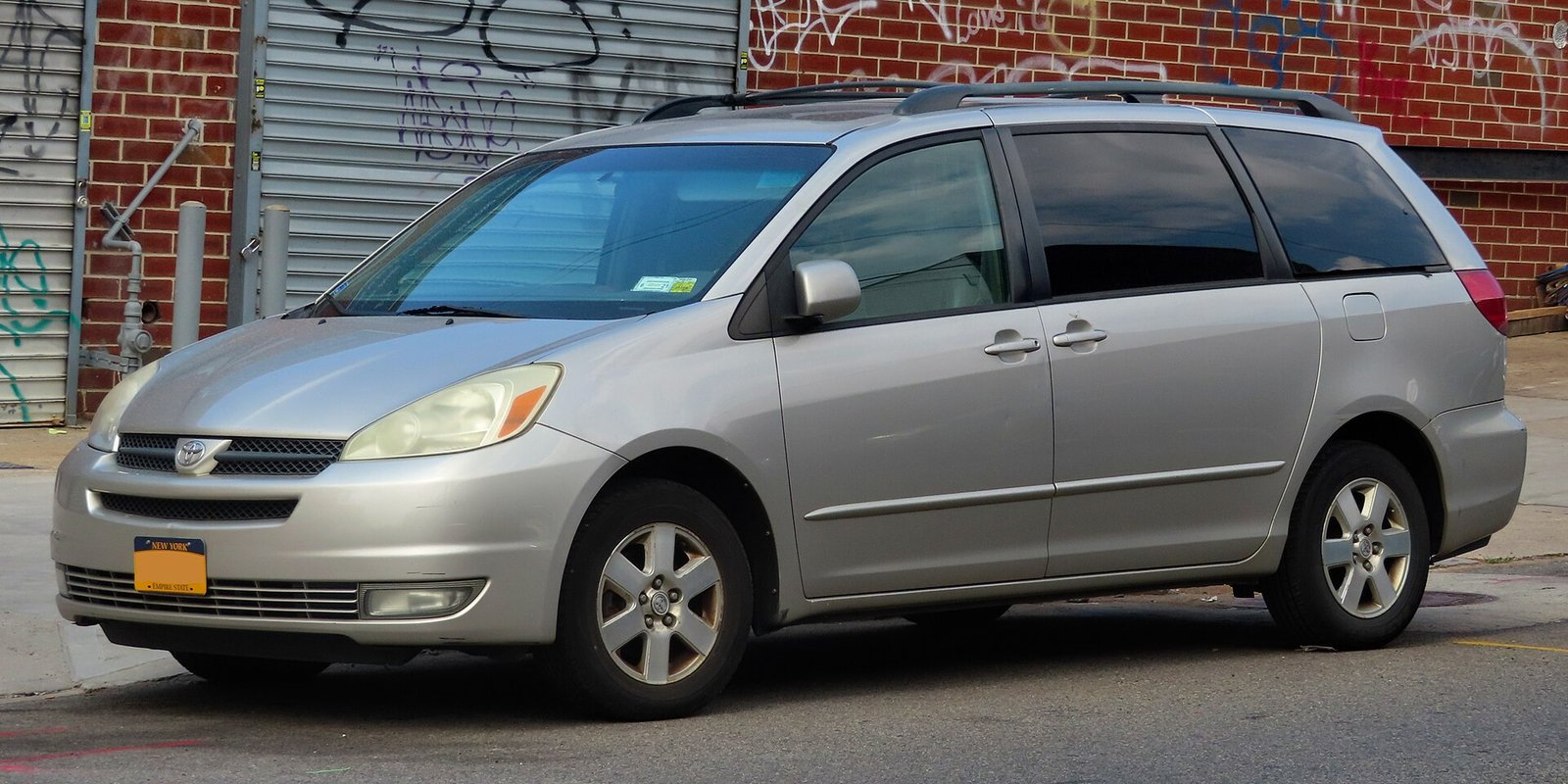 Silver 2004 Toyota Sienna XLE minivan parked on a city street, second generation model