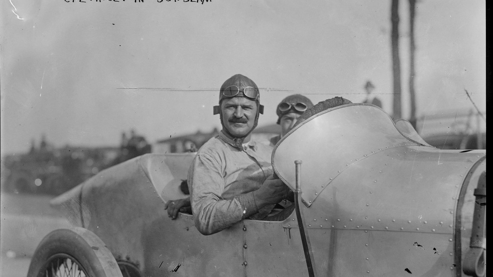Louis Chevrolet wearing goggles and a leather helmet, seated in a Sunbeam race car at Sheepshead Bay Speedway