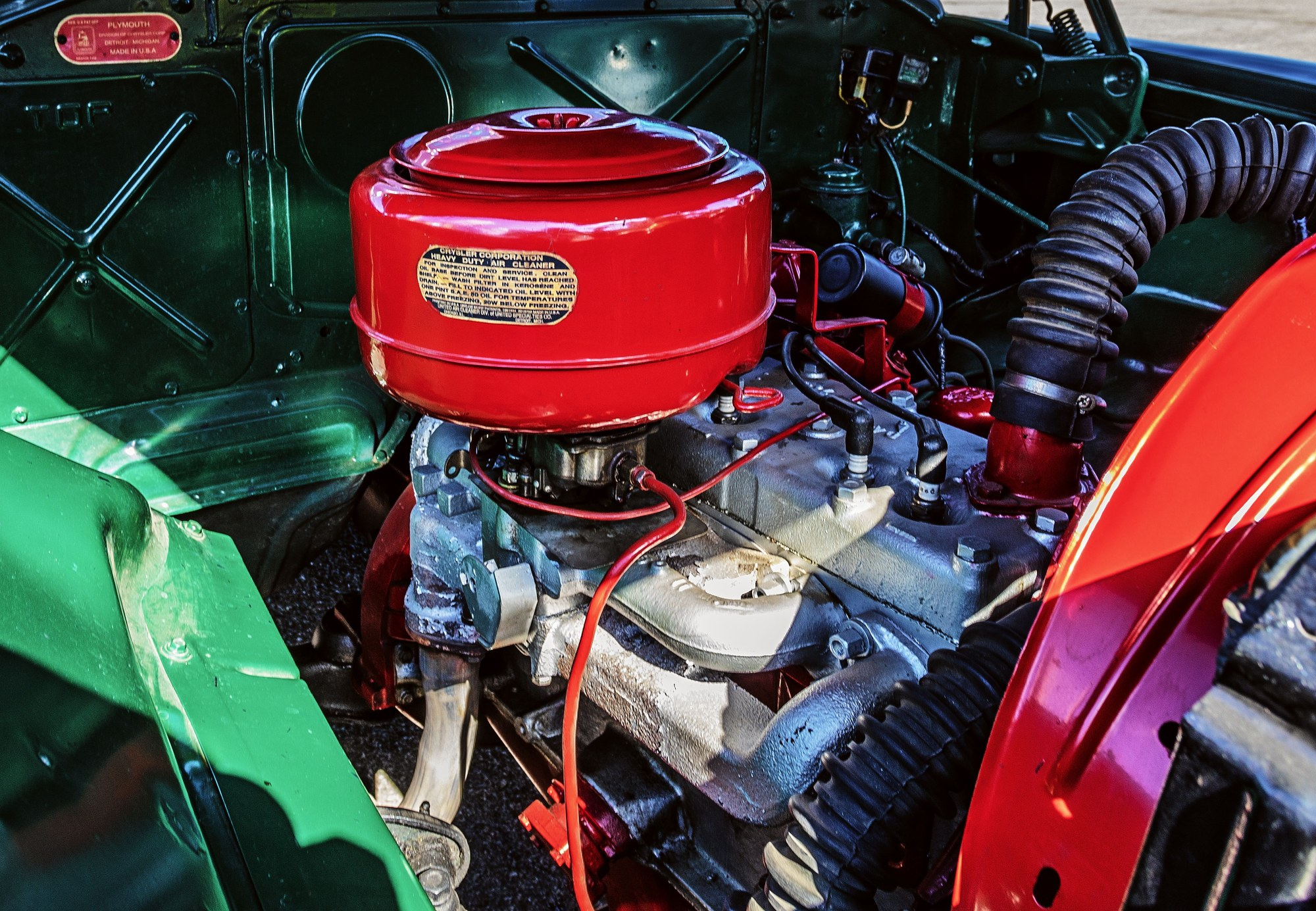 Vintage Plymouth engine bay with red air cleaner and ignition coil near the firewall