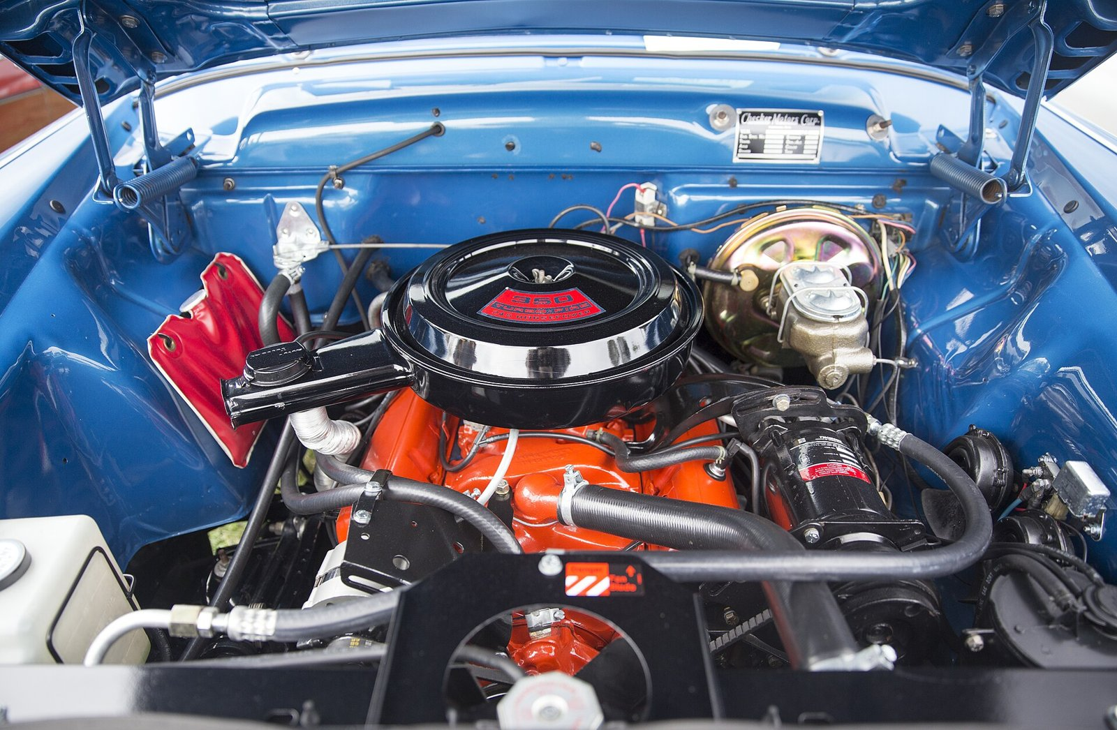 Restored Chevrolet 350 small-block V8 with orange block and black air cleaner in a 1972 Checker A12 engine bay