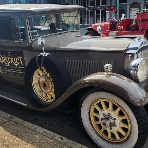 Vintage brown sedan with wire-spoke wheels and a side-mounted spare
