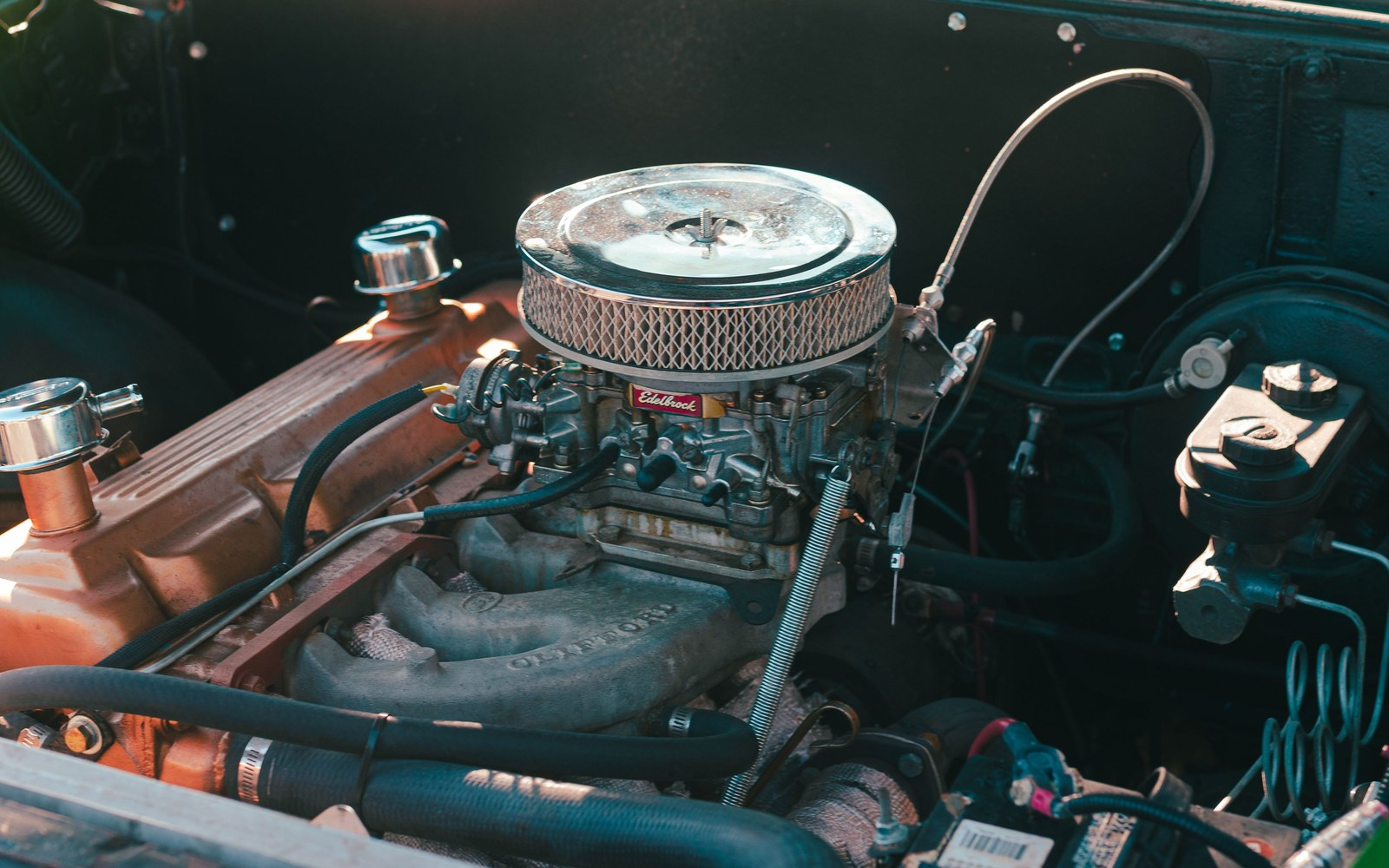 Carbureted small-block Chevy V8 in a classic car engine bay with a chrome air cleaner on a four-barrel carburetor