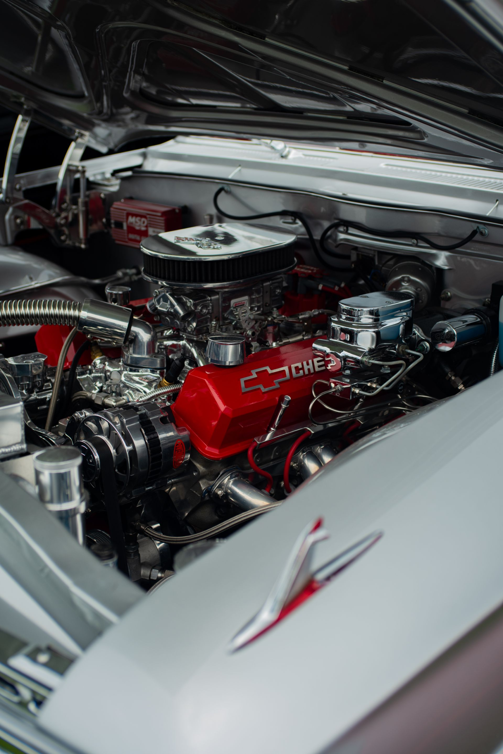 Restored small-block Chevrolet V8 with red Chevy valve covers and chrome air cleaner in a classic car engine bay